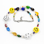 Close-up detail of HANAÉ Lucky Mood Charm Necklace showing colorful Venetian glass beads, yellow smiley charms, dice beads, freshwater pearls, and mixed textures.
