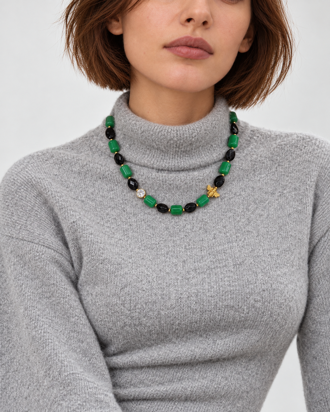 Model wearing LUMÉA Chromatic Stone Necklace featuring vibrant green jade, faceted black agate, and Swarovski crystal accents, styled with a gray knit sweater.