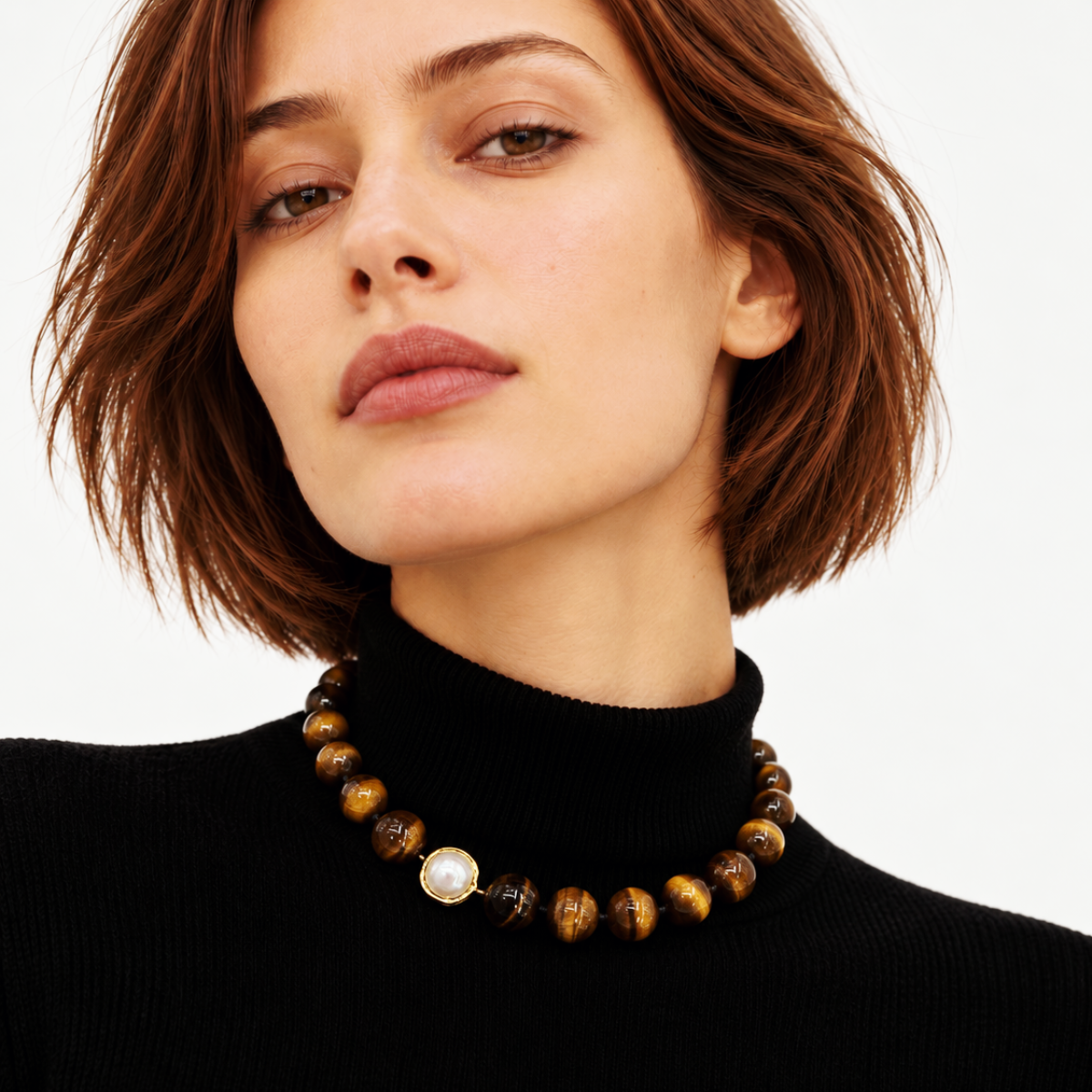 LUMÉA handcrafted brown tiger eye gemstone necklace with a pearl accent, styled over a black turtleneck on a female model.
 복사